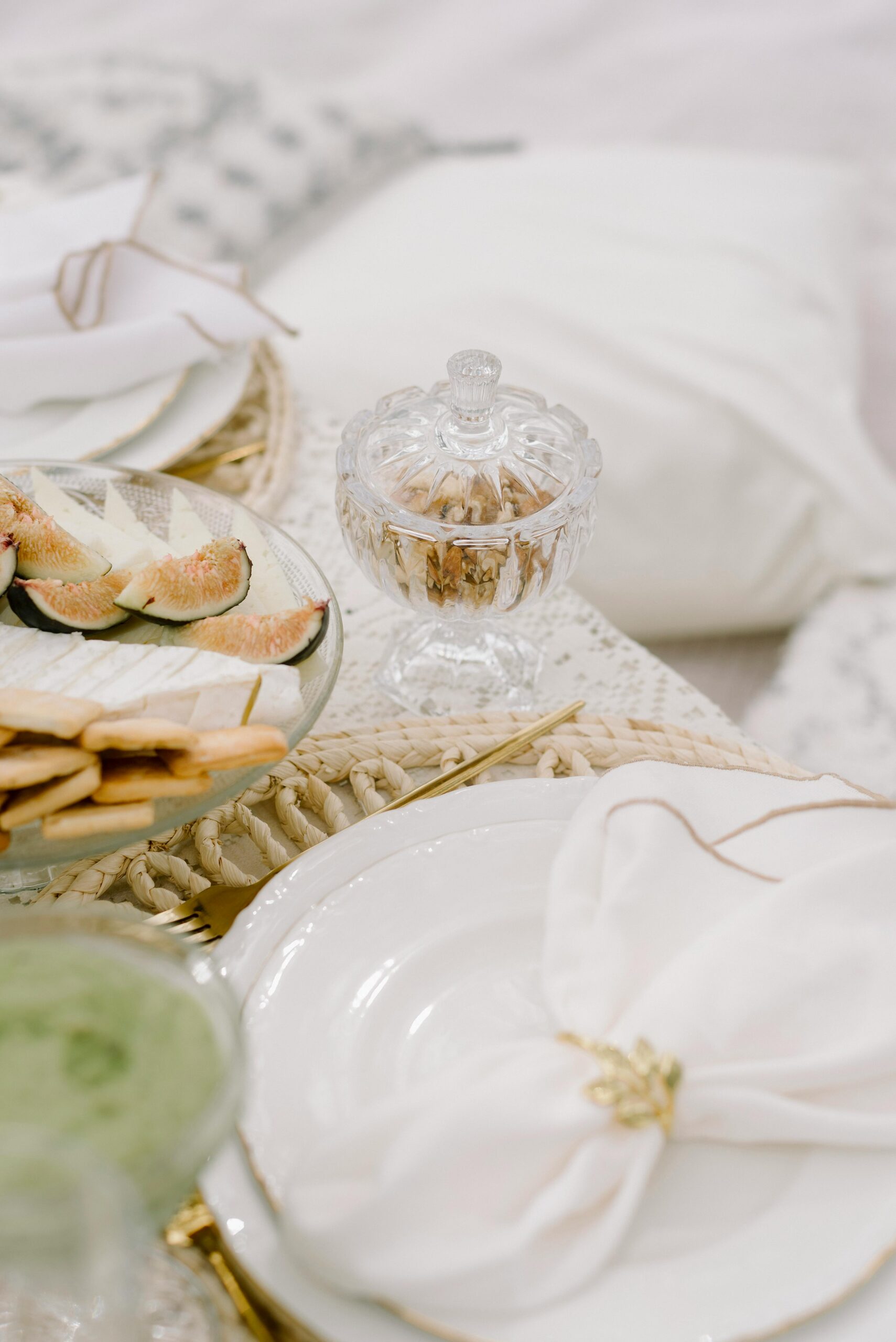 A refined table setup featuring a crystal sugar bowl, fresh figs, and white napkins, exuding sophistication.